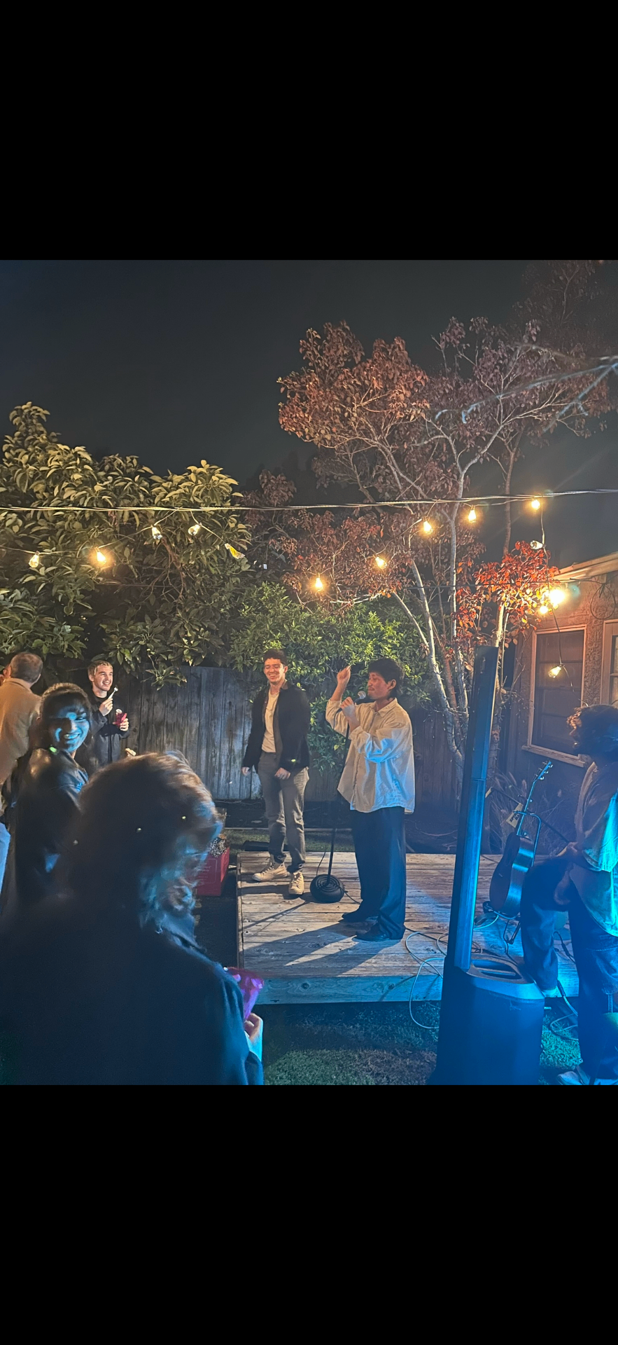 Outdoor Frontier NYC gathering with a live performance under string lights