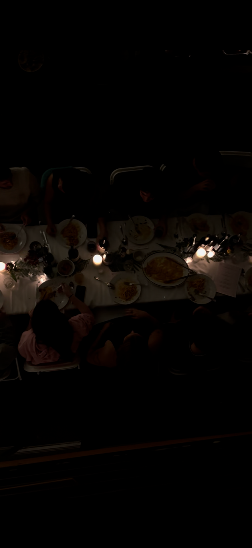 Moody overhead scene of guests sharing dinner by candlelight